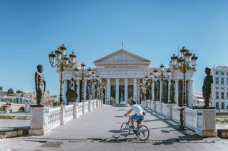 Man on bike riding across bridge to Macedonia Museum